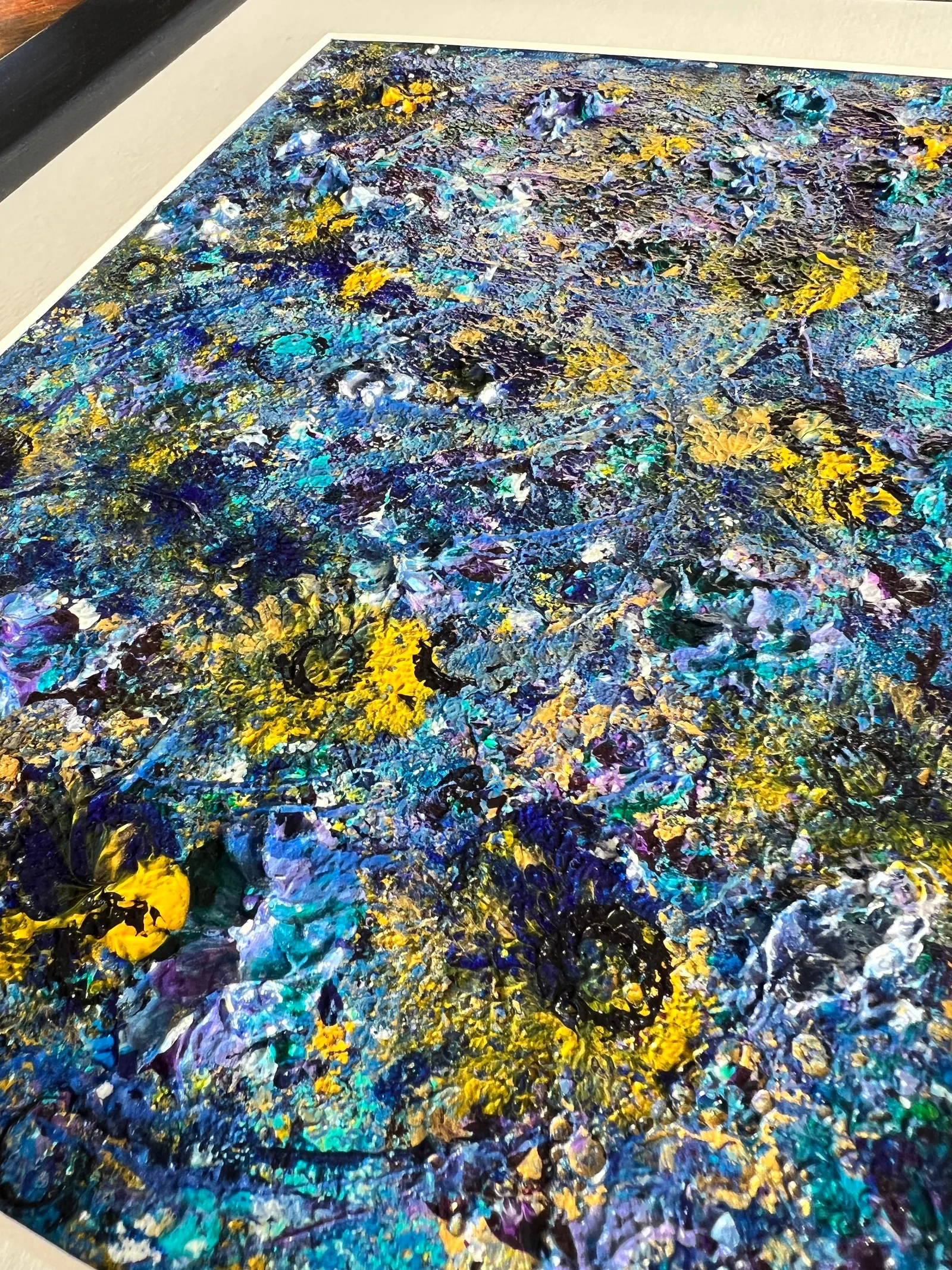 Angled close-up of the raised paint textures in Beginning - Sunflower Edition beside its white mount.