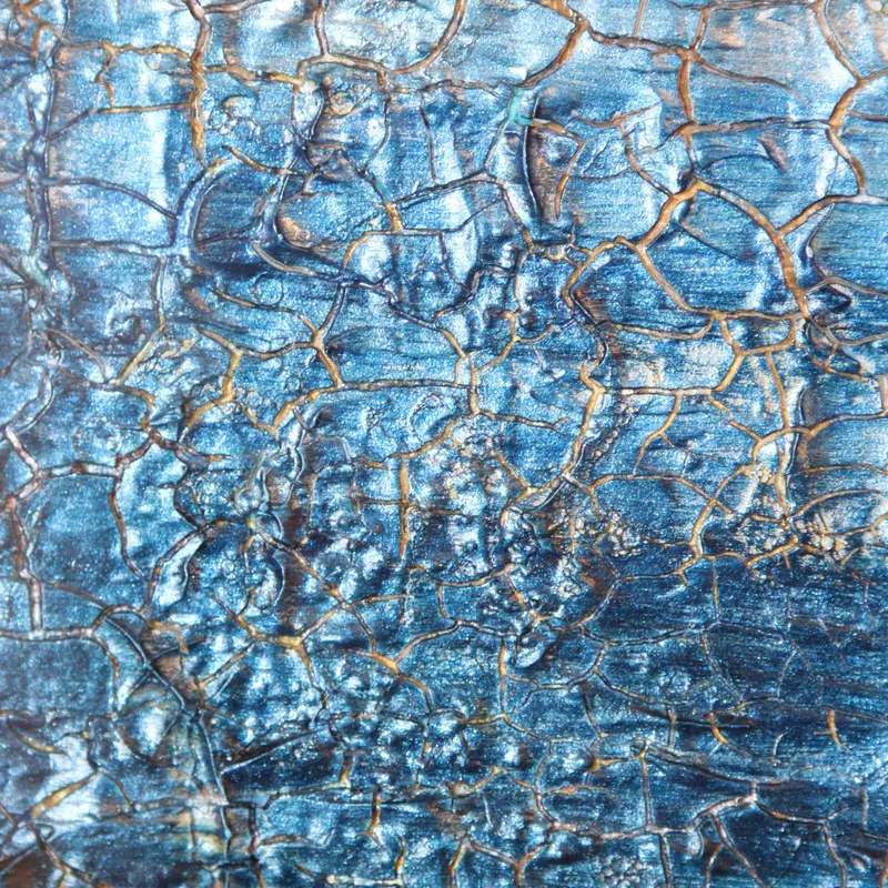 A close-up of crackled metallic blue KNH abstract artwork with fine gold lines.