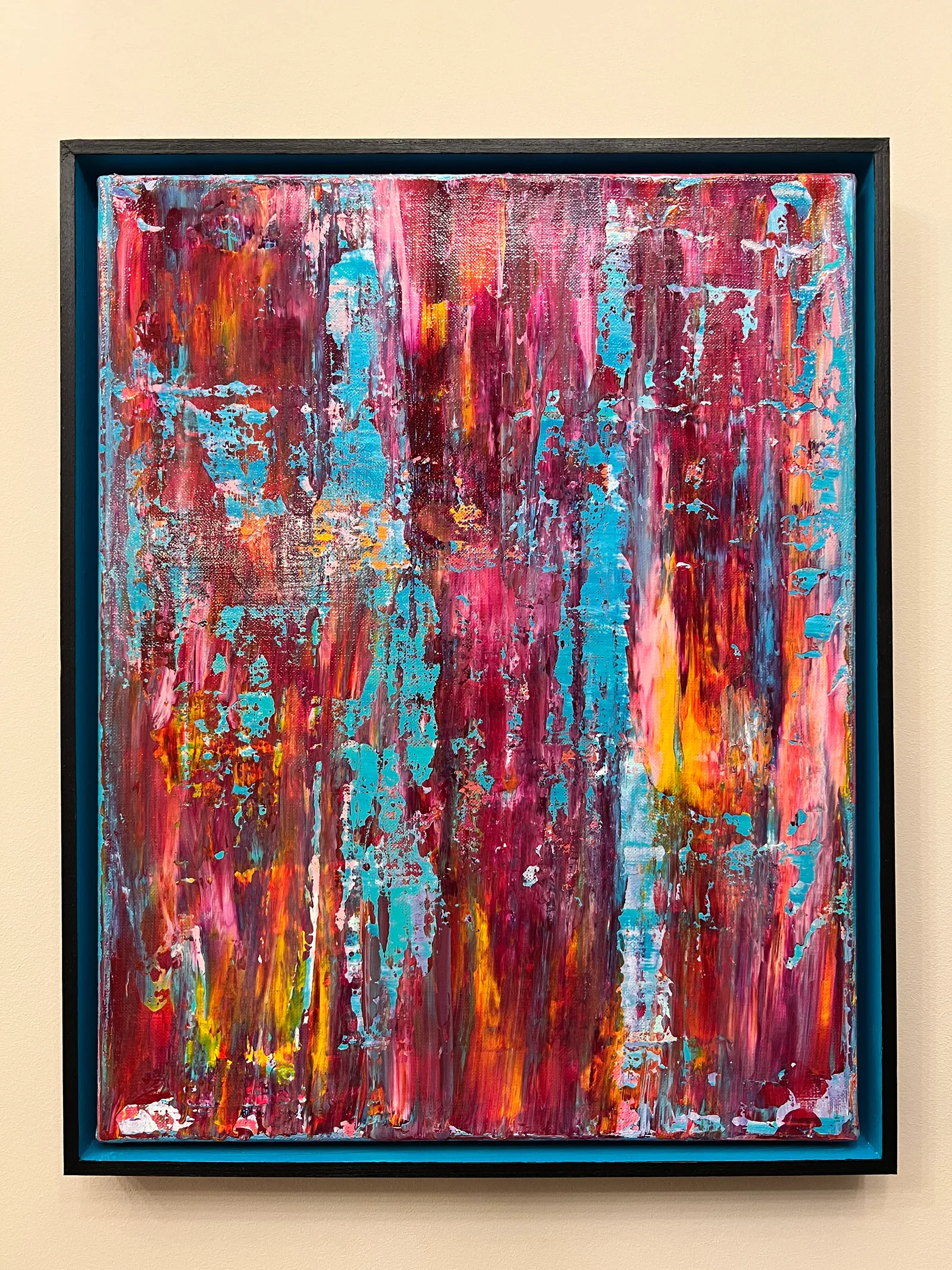 Malibu, a textured abstract painting in pink, red, turquoise and orange in a dark reclaimed wood frame with a turquoise inner edge against a white background.