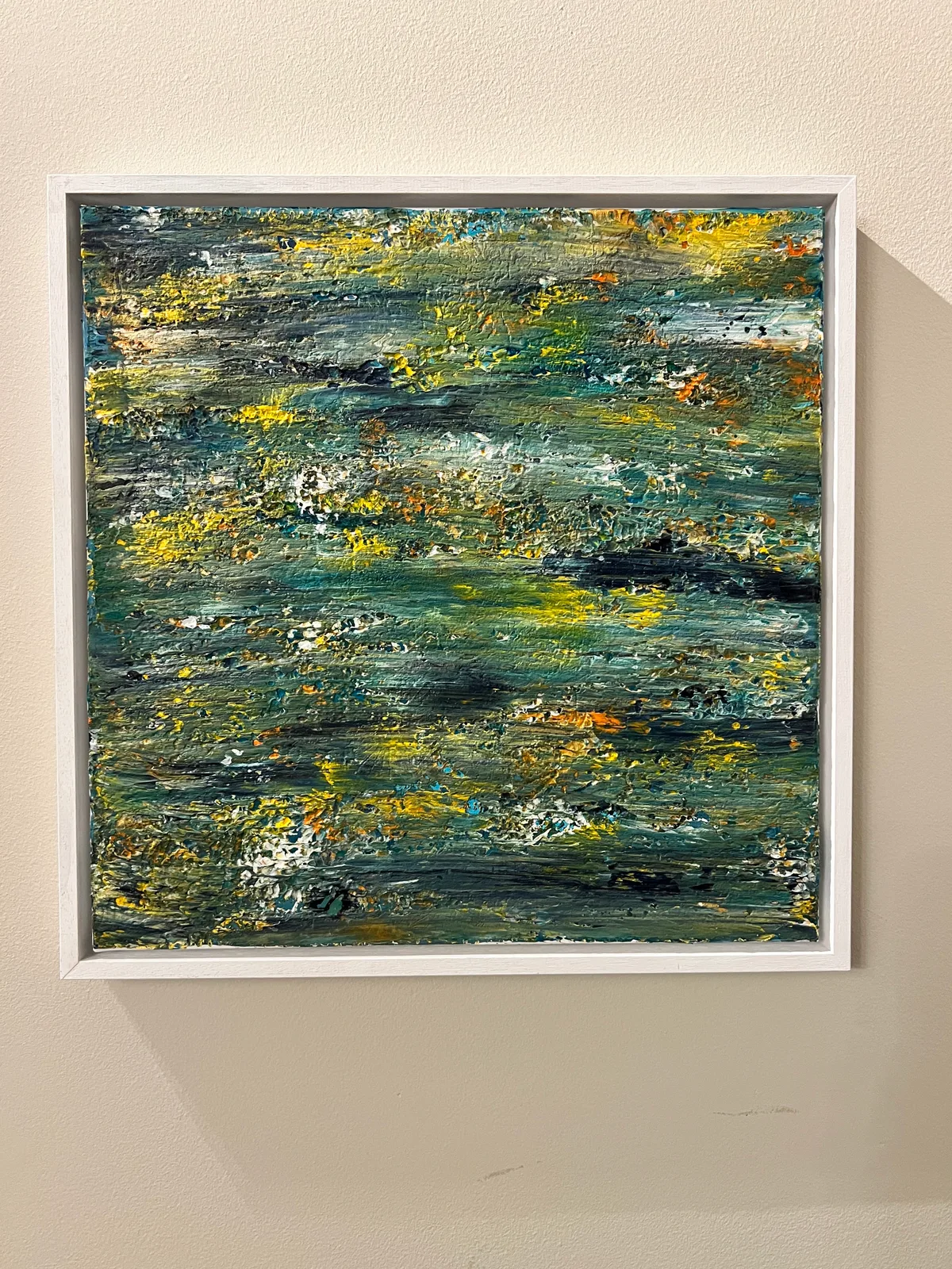 Somewhere Between, a green, blue and yellow abstract painting in a white wooden frame.